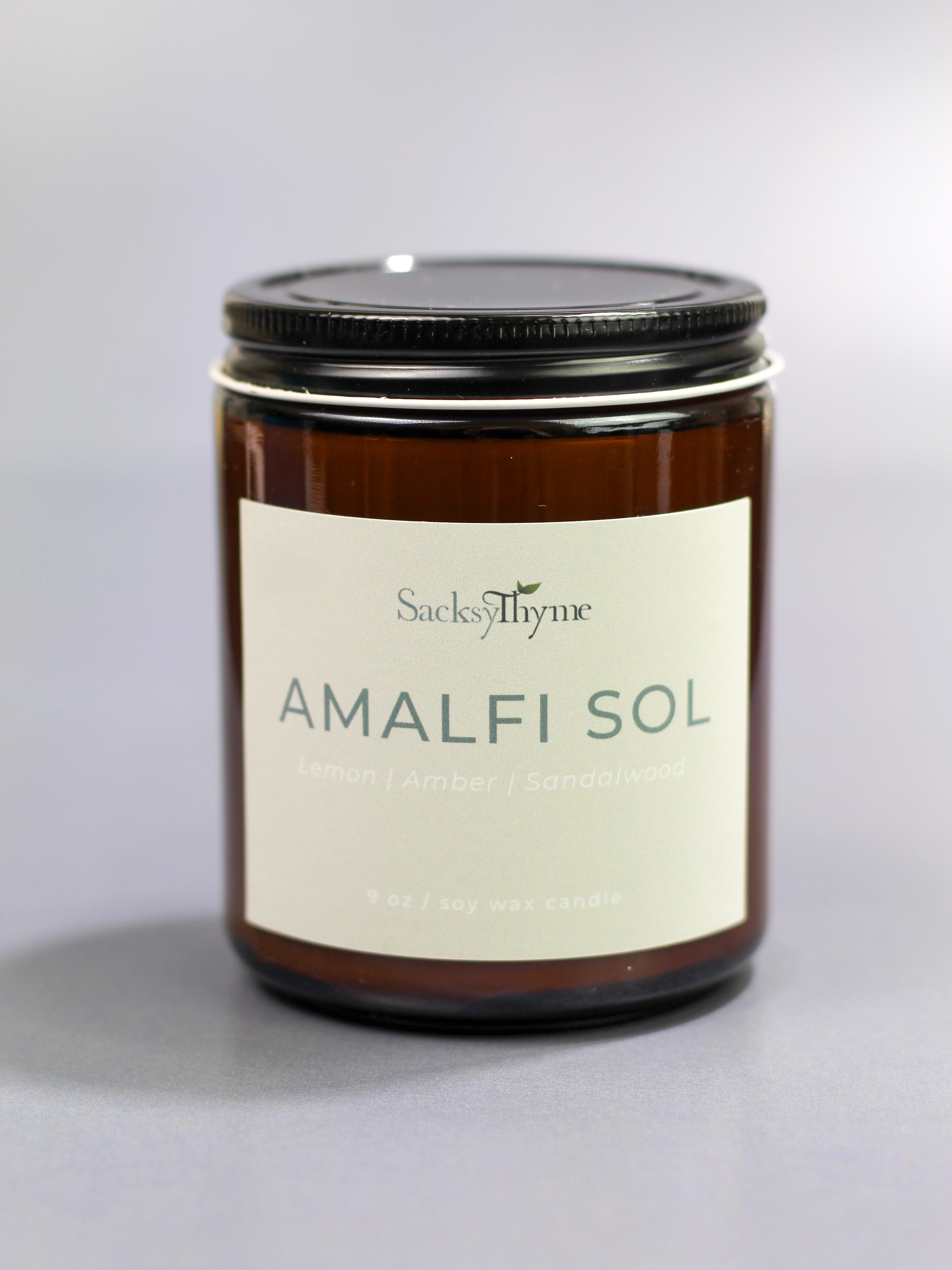 Candle jar labeled 'Amalfi Sol' by Sack of Thyme on a gray background