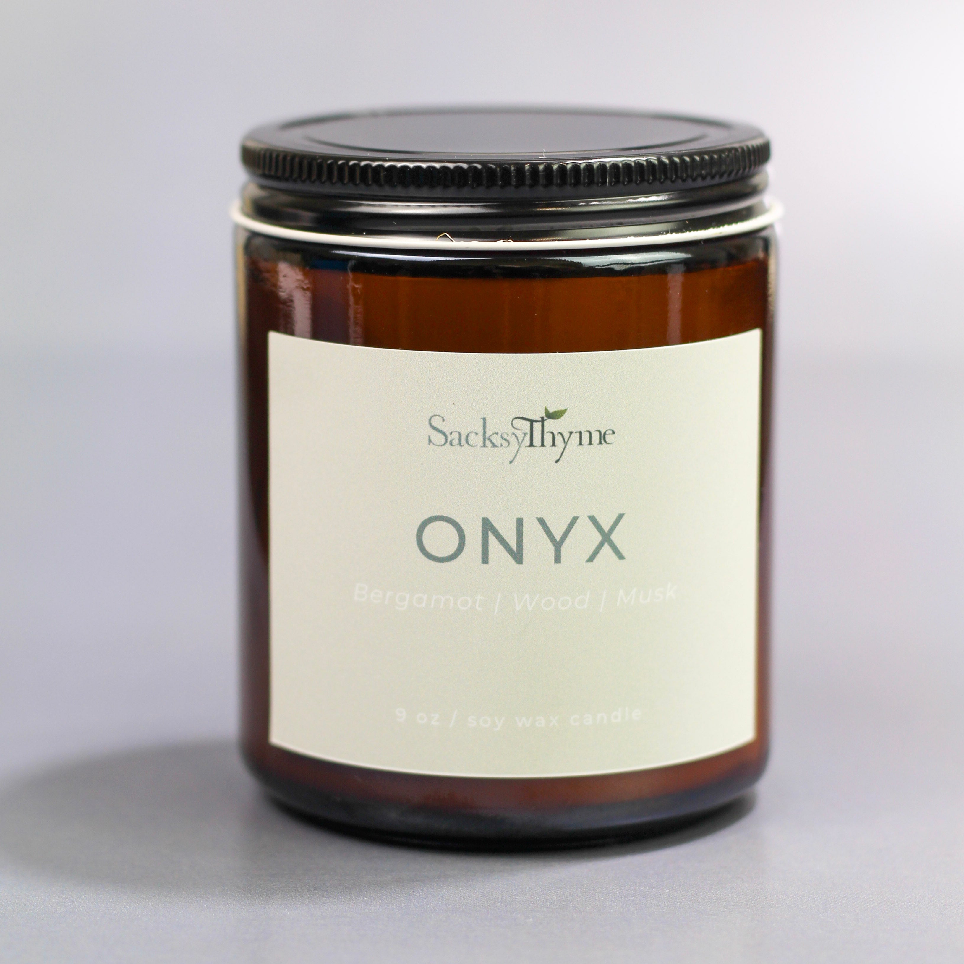 Candle jar labeled 'Onyx' by Sacksy Thyme on a gray background