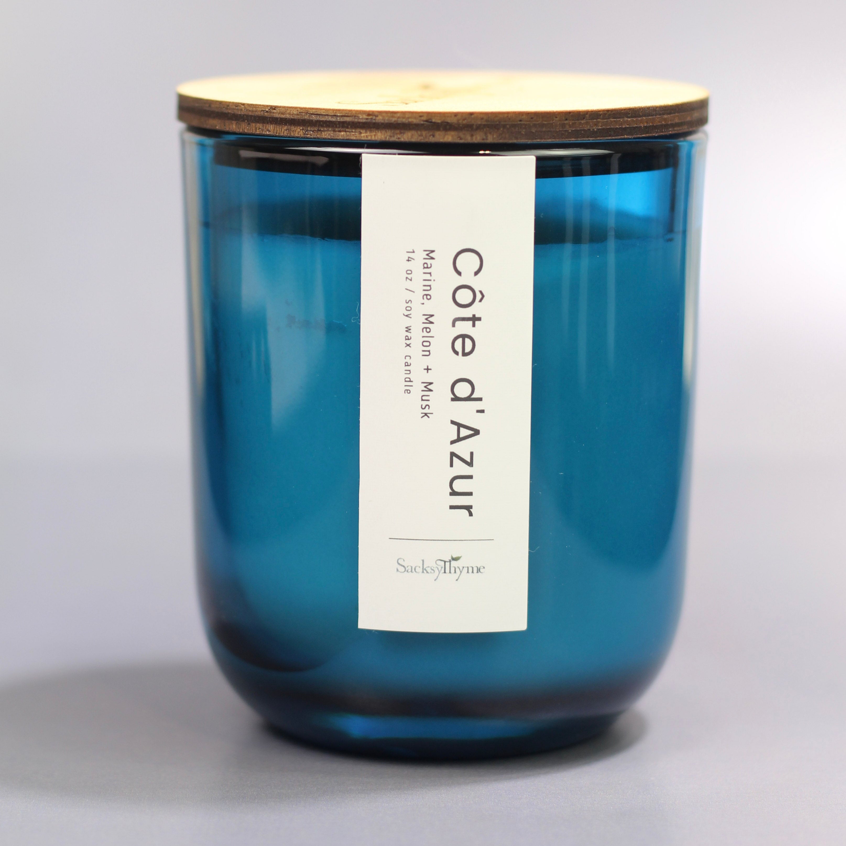 Blue candle with a wooden lid and 'Cote d'Azur' label on a gray background