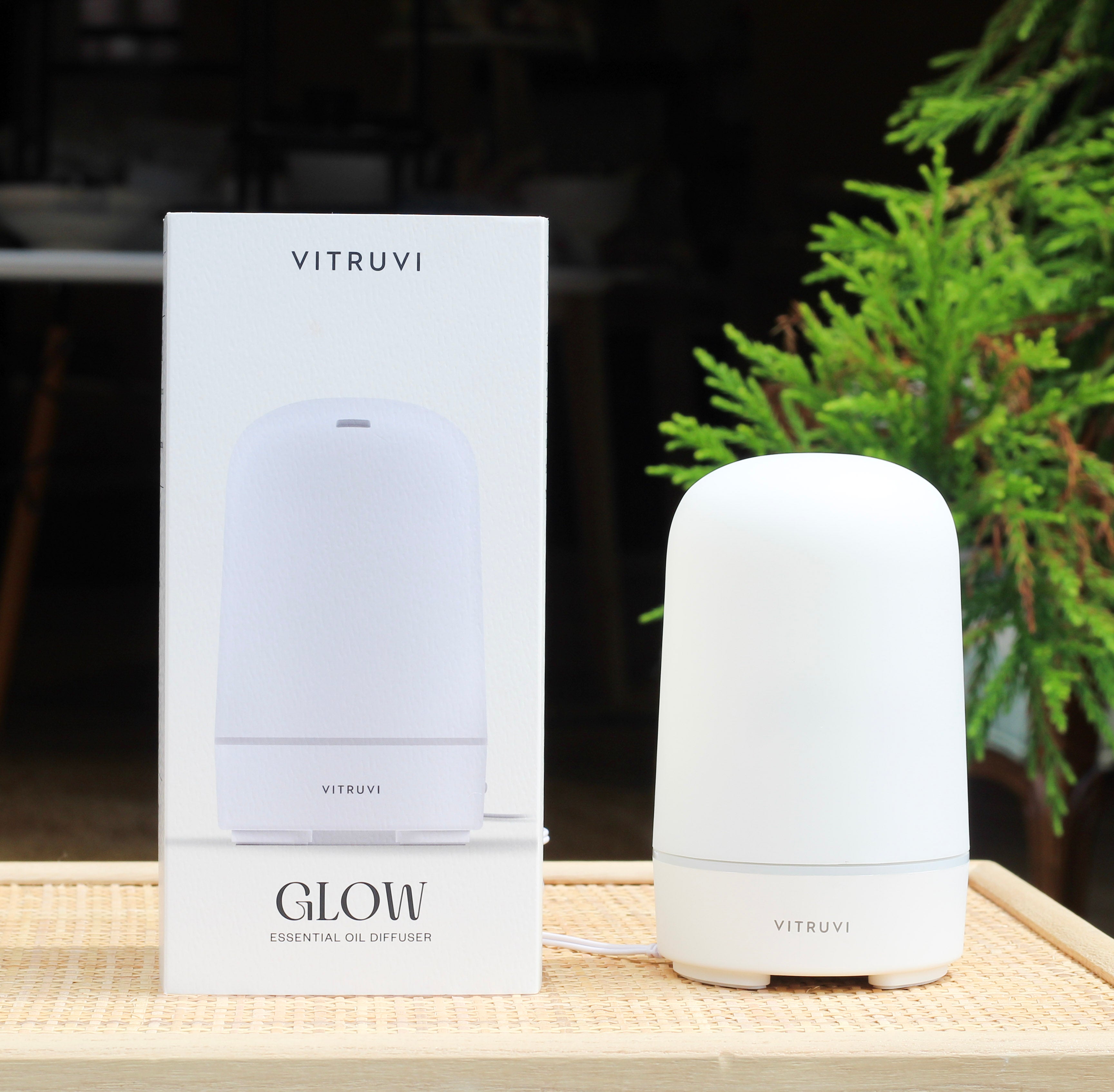 Vitruvi Glow essential oil diffuser with packaging on a wooden surface.
